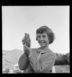 Unidentified girl holding a stone [axe head?], in an identified outdooor location