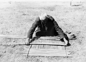 Unidentified Maori man constructing a screen backing for tukutuku work