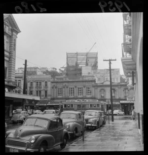 Shops on Lambton Quay, Wellington featuring Shell House (The Terrace) under construction and other buildings and businesses including Vance Vivian, Ferguson & Osborn Limited Printers and Bookbinders, and De Rezke [hairdressers]