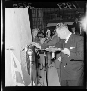 Hugh Watt, Minister of Works and Electricity, cementing a plaque to a wall, at a stone-laying ceremony at a departmental building, Wellington