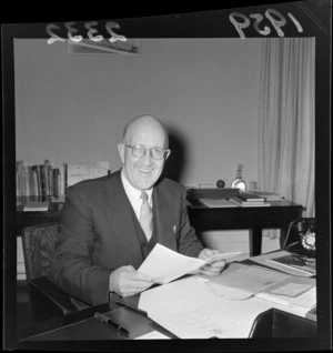 Arnold Nordmeyer, minister of finance, sitting at his desk, with the 1959 government budget, Wellington