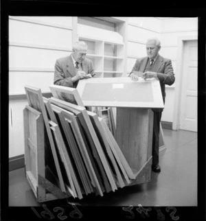 Two unidentified men taking an inventory of paintings, to be hung in the Kelliher Art Prize exhibition, Wellington