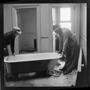 Demolition of Myer's home, Hobson Street, Wellington, showing two unidentified men shifting a bathtub