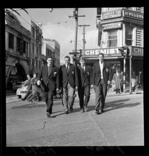 Group of unidentified members of the British and Irish Lions rugby team, crossing Willis Street at Perrett's Corner, including view of the Roxy Theatre on Manners Street