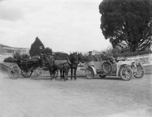 Men riding in a horse-drawn wagon and a motorcar