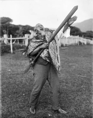 Unidentified elderly Maori man wearing a tag cloak and holding a taiaha