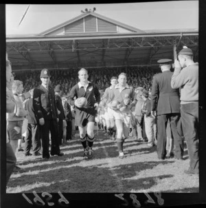 New Zealand All-Blacks vs British and Irish Lions second rugby test match, at Athletic Park, Berhampore, Wellington, showing captains Wilson Whineray and Ronnie Dawson leading teams onto field