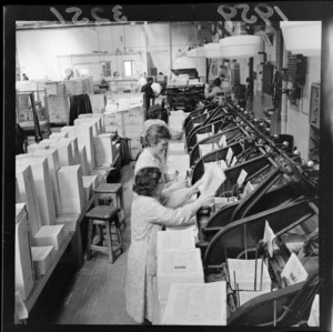 Telephone directory being produced at a bindery, showing two unidentified female workers operating machinery, probably Wellington region