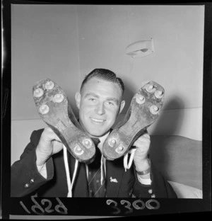 New Zealand All Black Donald Clarke, holding a pair of football boots