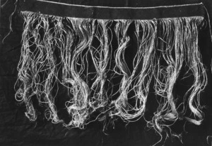 A skirt made of string like cords hanging from a woven waist band, probably photographed at Koroniti