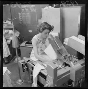 Unidentified woman using a pressing machine, at a Lower Hutt factory, Wellington
