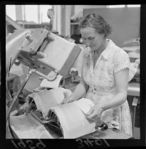 Unidentified woman pressing shirt cuffs, on a machine, at a Lower Hutt factory, Wellington