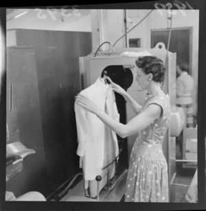 Unidentified woman putting a shirt through a [drying?] machine, at a Lower Hutt factory, Wellington
