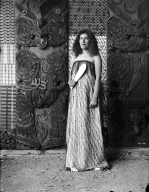 Pringle, Thomas, 1858-1931 :Guide Maggie Tawhai, with mere, standing alongside a carving in Te Rauru meeting house at Whakarewarewa