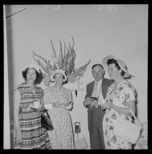 Personalities at the Tauherenikau Racecourse with three unidentified women and a man indoors dressed for the occasion, Wairarapa District