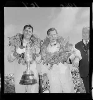 Jack Brabham with trophy, and Bruce McLaren at the New Zealand Grand Prix, Ardmore Airport, Manukau, Auckland