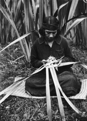 Woman weaving a food basket (rourou or kono) from flax leaves, at Koroniti