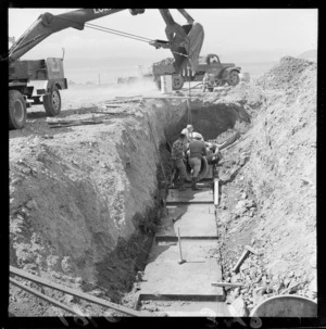 The laying of drains during reclamation work at Ngauranga Gorge with unidentified workman, Wellington City