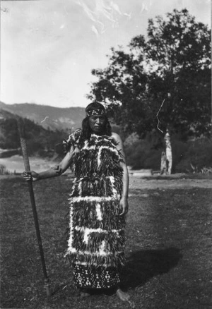 Photograph of Ada Pokiha modeling a fine feather cloak with a taniko border, at Koroniti