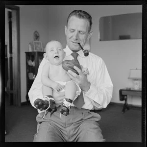 Neill McGregor holding miniature rugby ball and his baby grandson Neill Thomas McGregor wearing small sized rugby boots