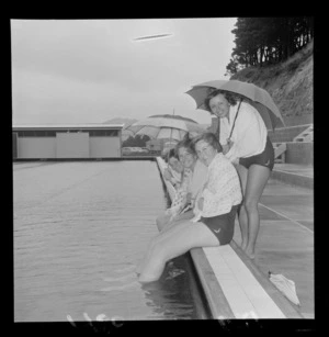 Four unidentified college girls at Wellington East Girls College Swimming baths with umbrellas, Wellington City