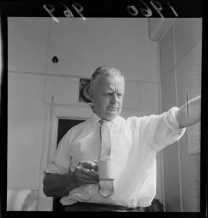 Evening Post cartoonist Neville Lodge in his office having a coffee, Wellington City