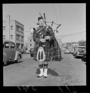 Scottish Bagpiper Ian White in full dress pipe band uniform standing on [Wakefield Street?], Wellington City