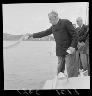 Unidentified men on boat, with man scattering the ashes of Mr C V Wagstaff at sea, Evans Bay, Wellington