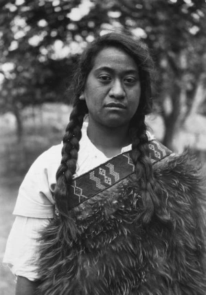 Photograph of a young woman wearing a kiwi feather cloak (kahu kiwi)