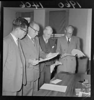 Minister of Mines, Mr Fred Hackett reading coal agreement with Japanese delegate and two other unidentified men