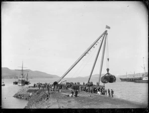 Crowd watching sheer-legs crane (set up on landfill at Port Chalmers), hoisting boilers preparatory to loading a ship at Port Chalmers.