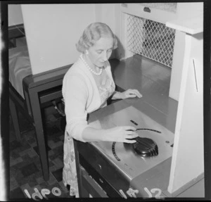 Unidentified woman standing in betting booth, testing the new betting machine, at Trentham Racecourse, Lower Hutt, Wellington