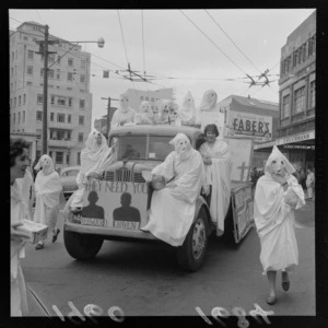 Unidentified students, during capping procession in Wellington, wearing white costumes, including a truck with a sign reading 'They Need You, Verwoerd Craven'