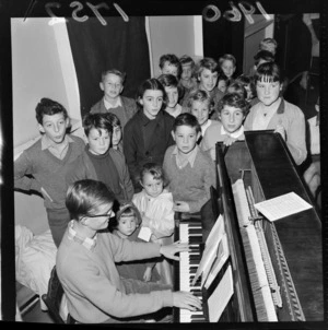 Harold Moar playing the piano, to accompany a group of unidentified children, location unidentified