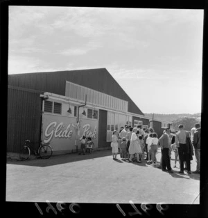Members of the public queuing for entry into 'Glide Rink' rollerkating rink, Kilbirnie, Wellington, including signage on exterior of building
