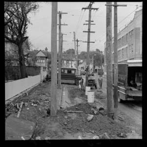 Trolley poles being [erected?] by unidentified workmen in upper Willis Street opposite the Dental Clinic looking to Brooklyn Hill, Wellington City