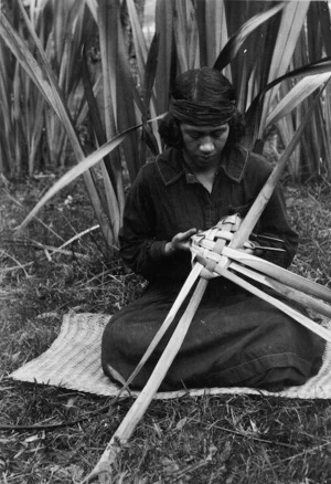 Woman weaving a food basket (rourou or kono) from flax leaves, at Koroniti