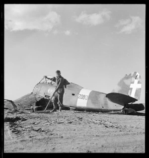 Wrecked Italian aeroplane, and soldier searching for land mines, Tripoli, Libya, World War 2