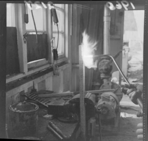 Timber treatment at an unknown wood processing plant with man testing the fire resistance of treated wood with a blow torch, Lower Hutt, Wellington Region