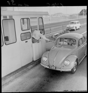 Driver in a Volkswagen Beetle paying the toll fee for crossing the Auckland Harbour Bridge