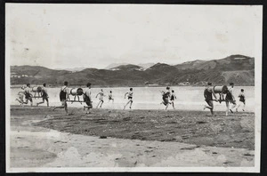 Teams of men running with reels during opening day event, Lyall Bay beach, Wellington