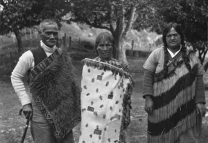 Photograph of three people wearing cloaks and a piupiu