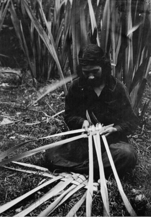 Woman weaving a food basket (rourou or kono) from flax leaves, at Koroniti