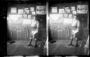 Unidentified man in a Scottish kilt, indoors, including photographs of Mount Cook and a pair of snow shoes on the wall behind, Mount Cook National Park, Canterbury Region