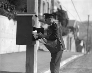 Unidentified postman retrieving mail from a postbox