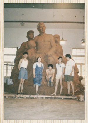 Five people in front of a large sculpture of Rewi Alley and children