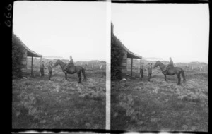 Unidentified men by house, one man on horse, unidentified location