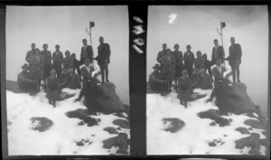 Unidentified group of men and women sitting and standing in the snow with one man holding a snowman, unknown location