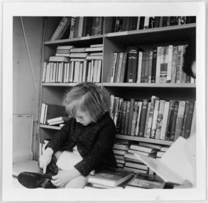 Child photographed against shelves of books