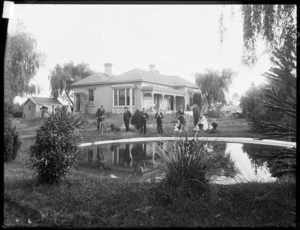 Group by a pond, in the garden of a house, probably in Christchurch